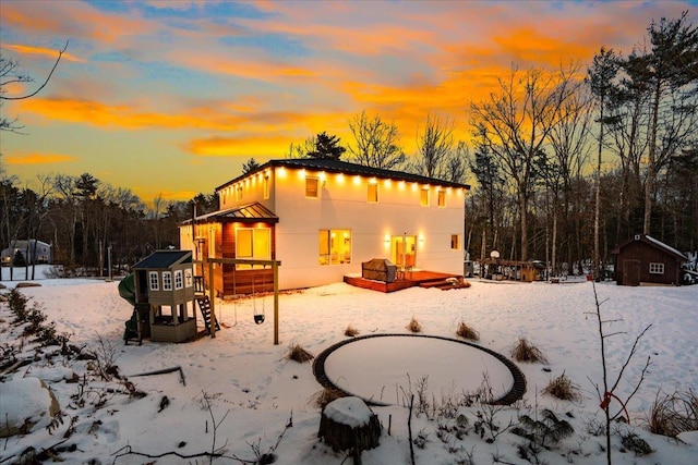 snow covered rear of property with a storage shed