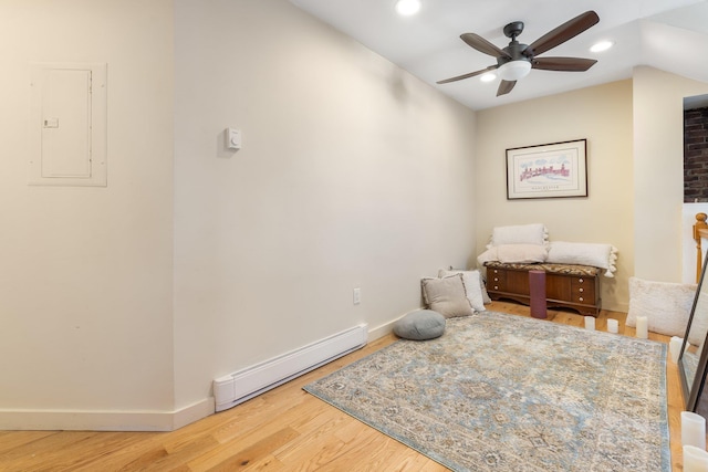 interior space with ceiling fan, wood-type flooring, electric panel, and a baseboard heating unit