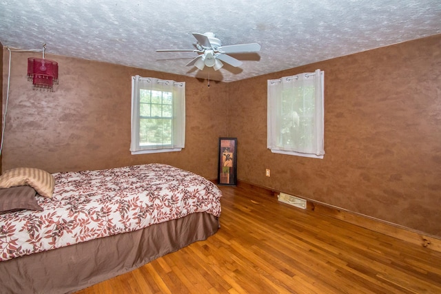 bedroom featuring wood-type flooring, ceiling fan, and a textured ceiling