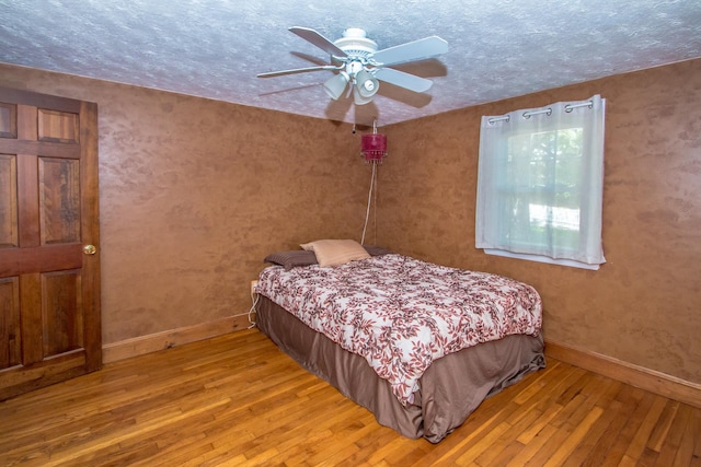 bedroom with ceiling fan, a textured ceiling, and light wood-type flooring