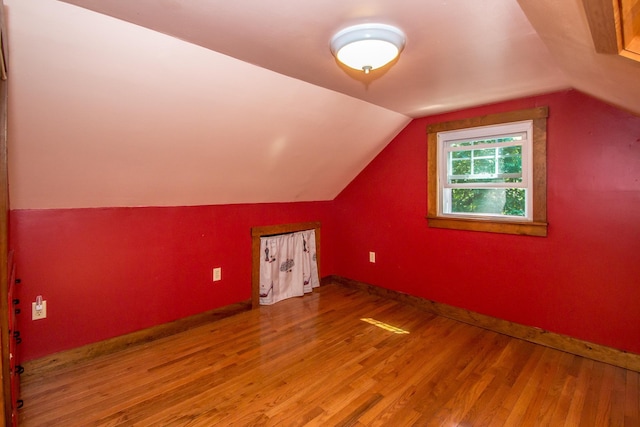 additional living space with hardwood / wood-style flooring and vaulted ceiling