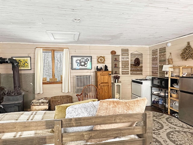 living room featuring wooden walls and a wood stove