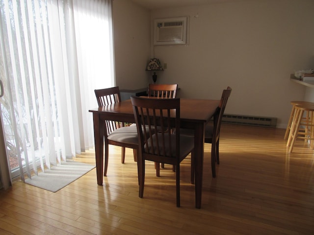 dining space with light wood-type flooring, a wall mounted AC, and baseboard heating