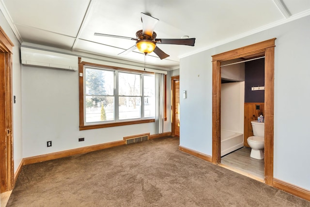 unfurnished bedroom featuring crown molding, an AC wall unit, carpet flooring, and ensuite bathroom