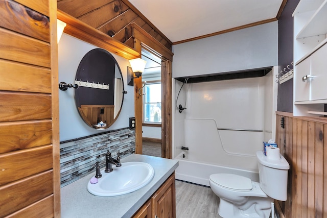 full bathroom featuring backsplash, vanity, toilet, crown molding, and washtub / shower combination