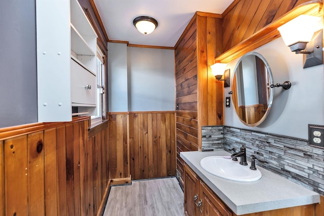 bathroom featuring vanity, ornamental molding, hardwood / wood-style floors, and wooden walls