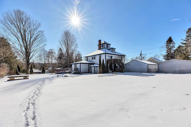 snow covered house featuring a garage and an outdoor structure