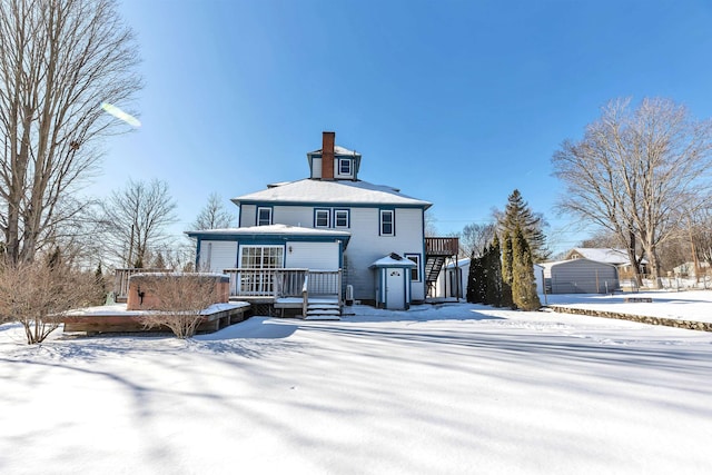 snow covered rear of property featuring a storage shed