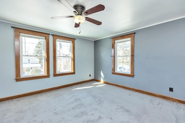 carpeted empty room featuring plenty of natural light, ornamental molding, and ceiling fan