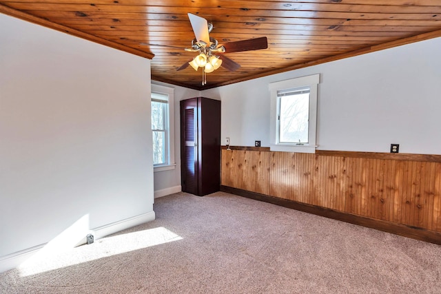 spare room featuring ceiling fan, wooden walls, light carpet, and wooden ceiling