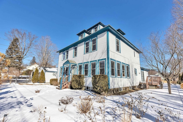 snow covered back of property featuring a deck