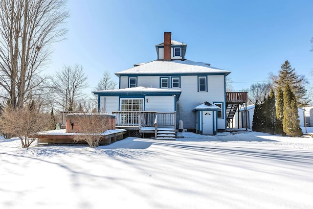 snow covered rear of property featuring a wooden deck