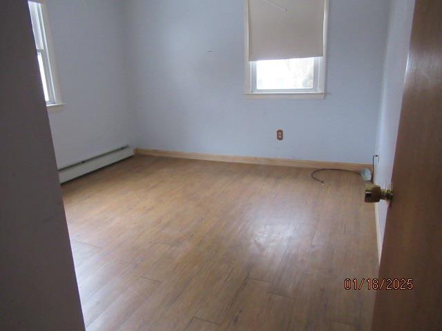 spare room with a baseboard heating unit and light wood-type flooring