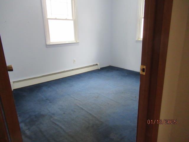 carpeted empty room featuring baseboard heating