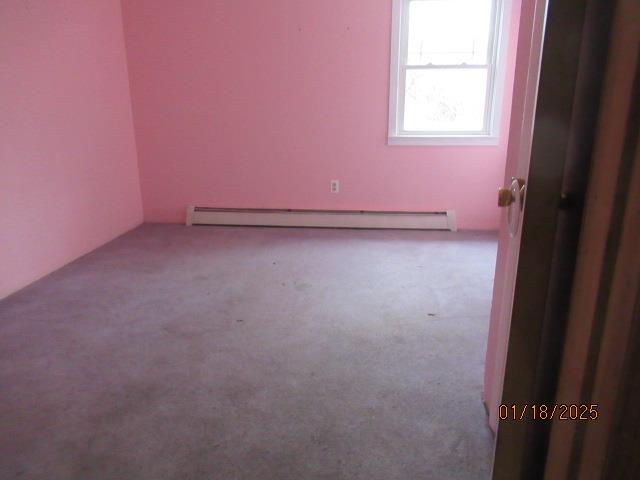 carpeted spare room featuring a baseboard heating unit