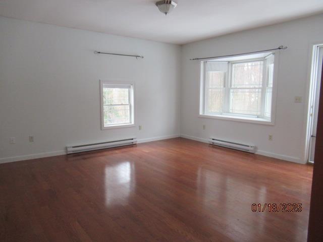 unfurnished room featuring hardwood / wood-style floors and baseboard heating