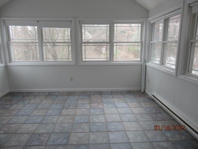 unfurnished sunroom with lofted ceiling and baseboard heating