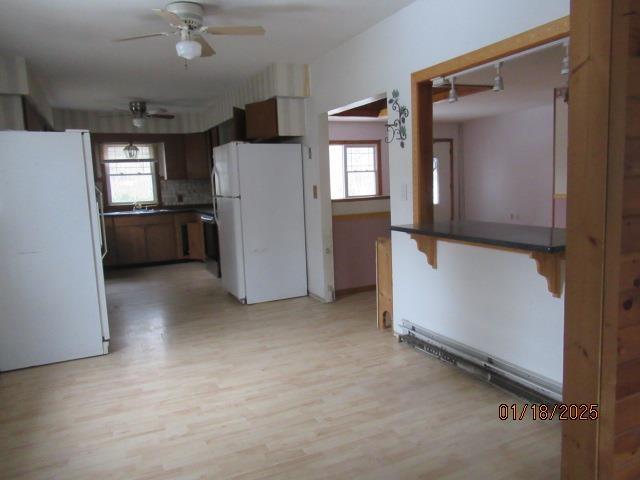 kitchen featuring white refrigerator, backsplash, ceiling fan, and light hardwood / wood-style flooring