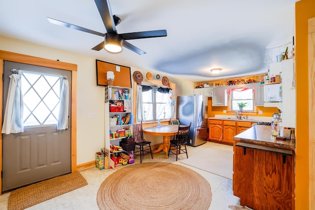 kitchen with ceiling fan, stainless steel fridge, sink, and white cabinets