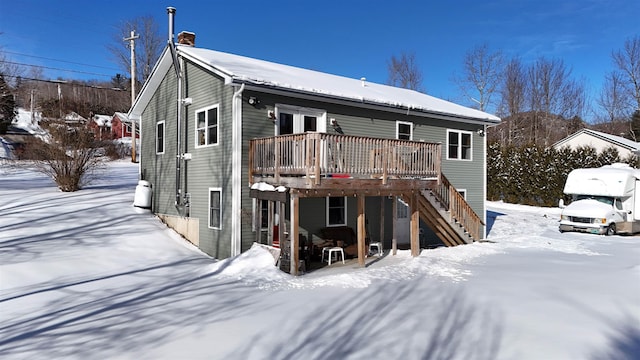 snow covered back of property featuring a wooden deck