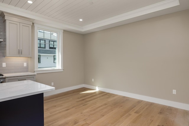 kitchen with crown molding, light hardwood / wood-style flooring, wooden ceiling, a tray ceiling, and backsplash