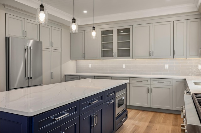 kitchen featuring hanging light fixtures, appliances with stainless steel finishes, light stone counters, and light hardwood / wood-style flooring