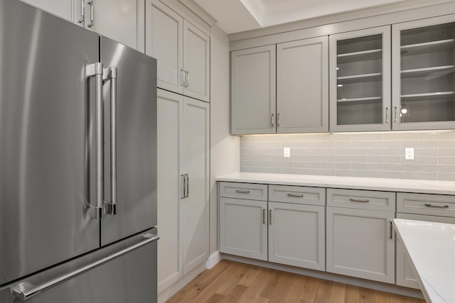 kitchen featuring gray cabinetry, high end fridge, light hardwood / wood-style flooring, and backsplash