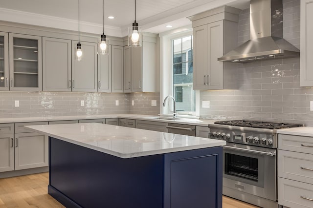 kitchen featuring wall chimney exhaust hood, light hardwood / wood-style flooring, appliances with stainless steel finishes, a kitchen island, and light stone countertops