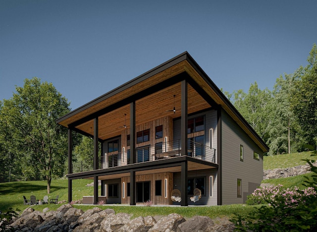 rear view of property with ceiling fan, a balcony, and a yard