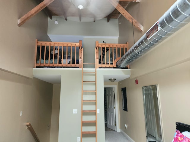 staircase with a towering ceiling, carpet floors, and beamed ceiling