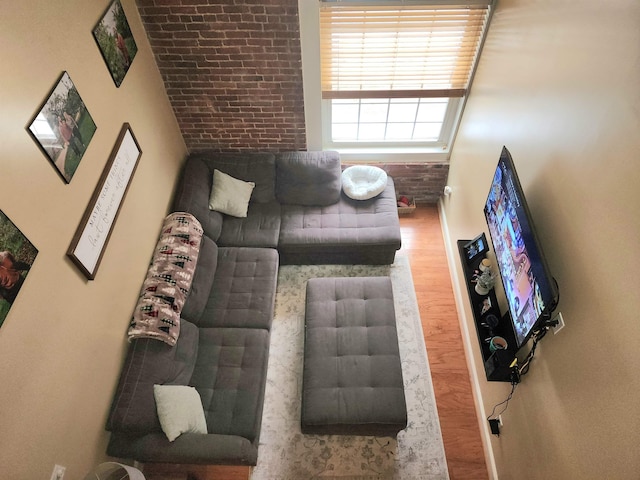 living room featuring wood-type flooring and brick wall