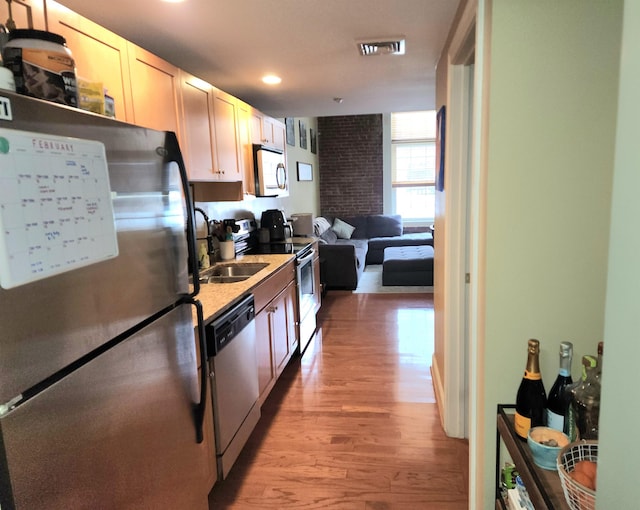 kitchen featuring appliances with stainless steel finishes, sink, and light wood-type flooring