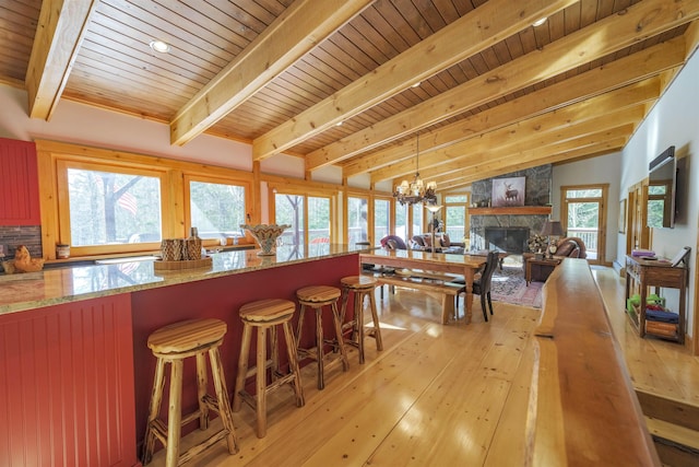 kitchen with a breakfast bar area, decorative light fixtures, a chandelier, a fireplace, and light hardwood / wood-style floors