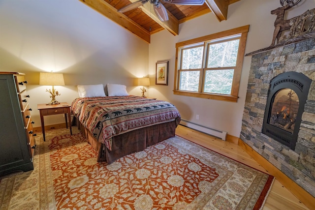 bedroom with wood ceiling, light wood-type flooring, a baseboard radiator, beamed ceiling, and a fireplace