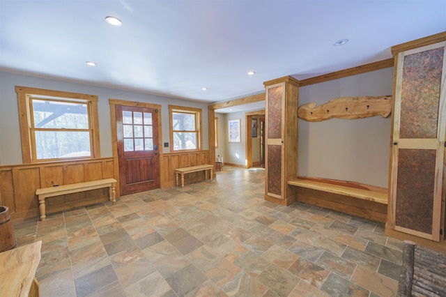 entrance foyer featuring ornamental molding and wood walls