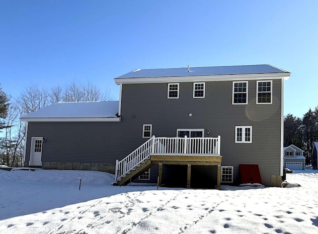 snow covered back of property featuring a wooden deck