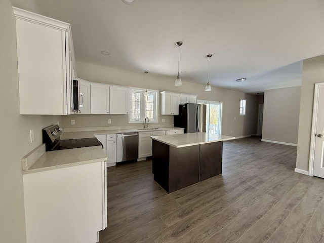 kitchen with pendant lighting, sink, white cabinetry, stainless steel appliances, and a kitchen island