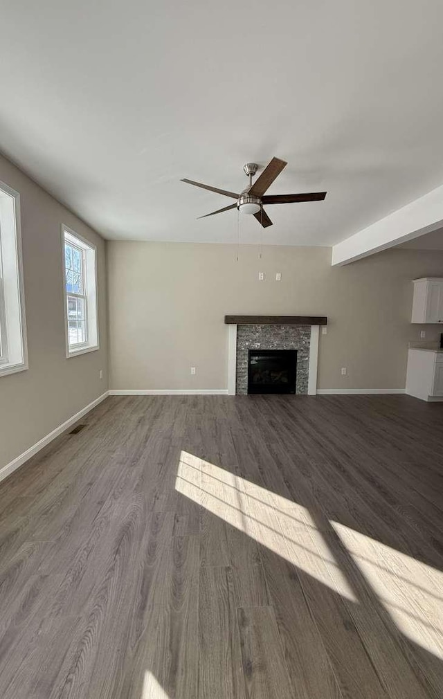 unfurnished living room with ceiling fan, wood-type flooring, and a tiled fireplace