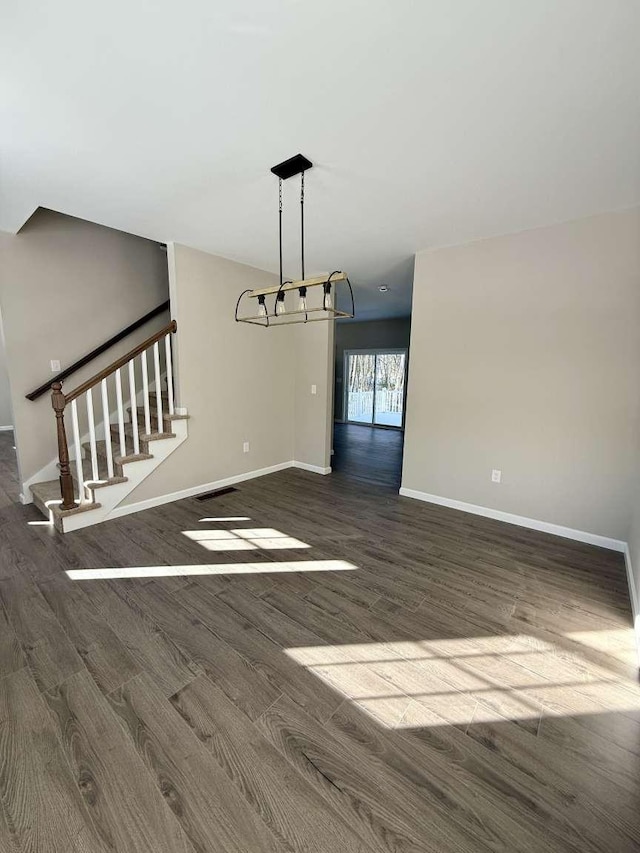 unfurnished dining area with an inviting chandelier and dark hardwood / wood-style flooring