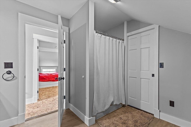 bathroom with vaulted ceiling, hardwood / wood-style floors, and a shower with shower curtain