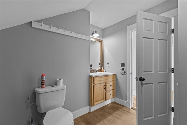 bathroom featuring vanity, hardwood / wood-style flooring, vaulted ceiling, and toilet