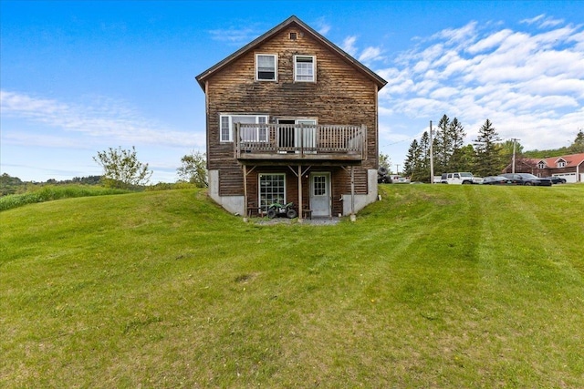 back of property featuring a wooden deck and a lawn