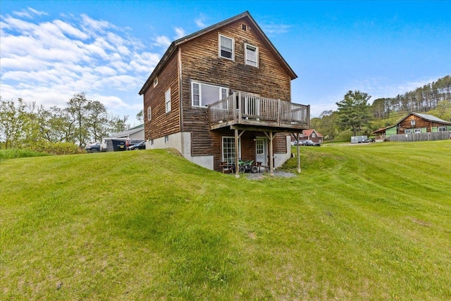 back of property featuring a wooden deck and a lawn