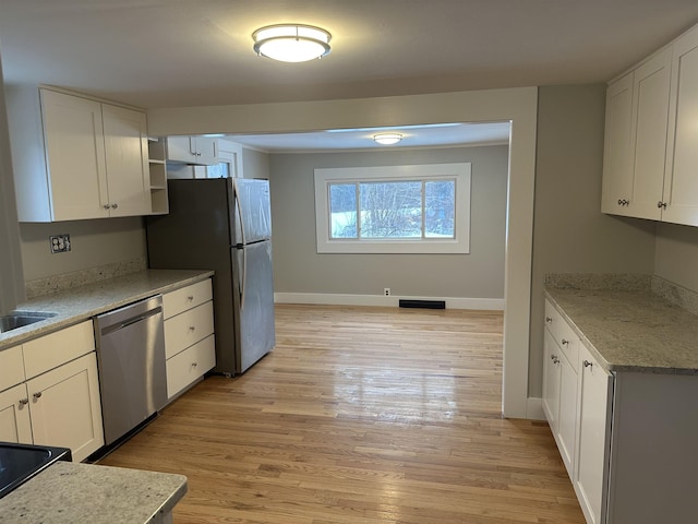 kitchen featuring white cabinetry, appliances with stainless steel finishes, light stone counters, and light wood-type flooring