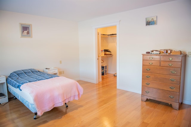 bedroom with a spacious closet, light wood-type flooring, and a closet