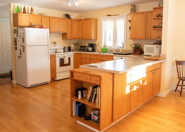 kitchen featuring sink, white appliances, kitchen peninsula, and light wood-type flooring