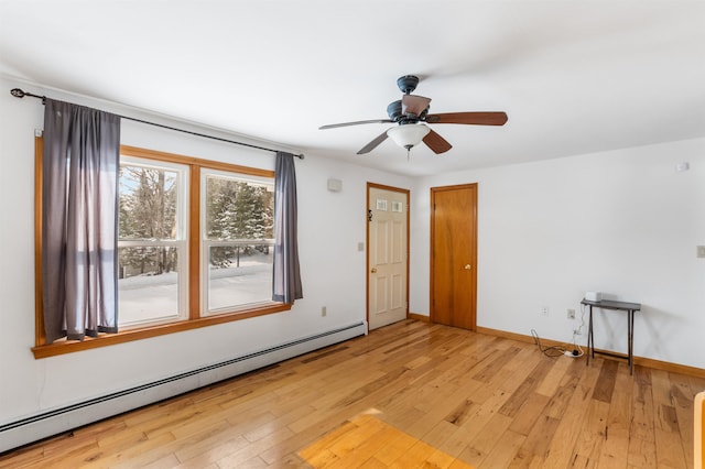 spare room featuring baseboard heating, ceiling fan, and light hardwood / wood-style flooring