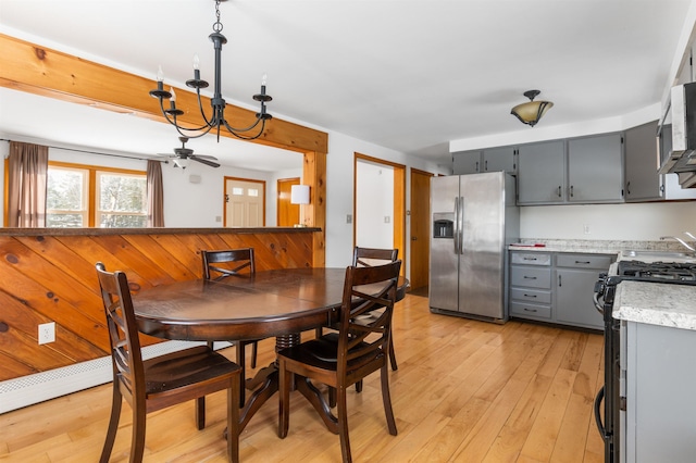 dining space with light hardwood / wood-style floors, a chandelier, and wood walls