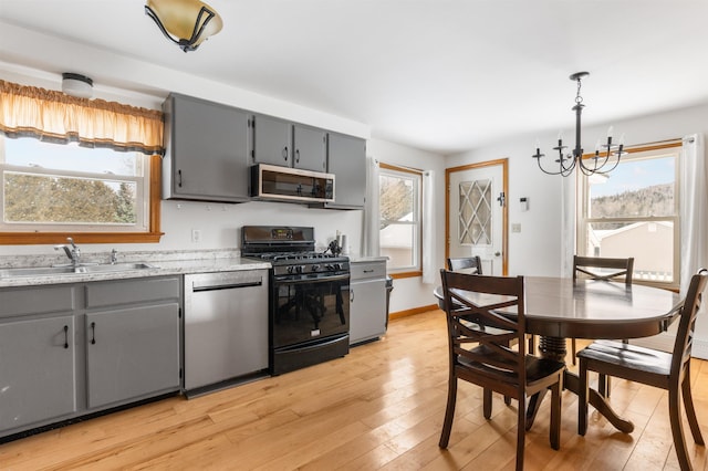 kitchen with sink, appliances with stainless steel finishes, gray cabinetry, hanging light fixtures, and a wealth of natural light