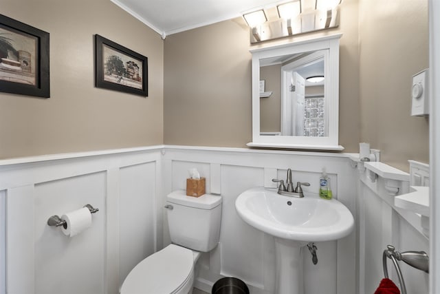 bathroom with ornamental molding, toilet, and sink